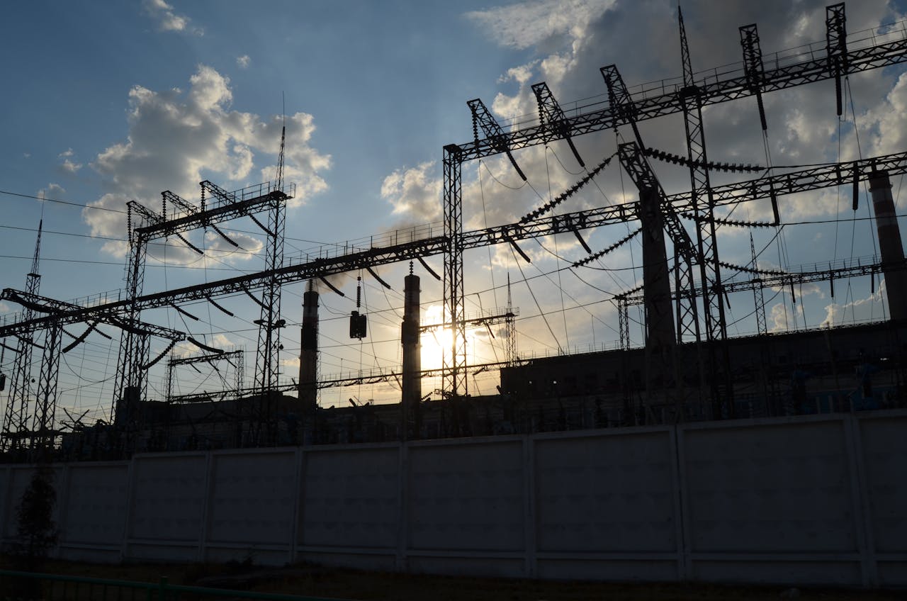 A striking silhouette of an electrical substation with the sun rising behind it, creating a dramatic sky.