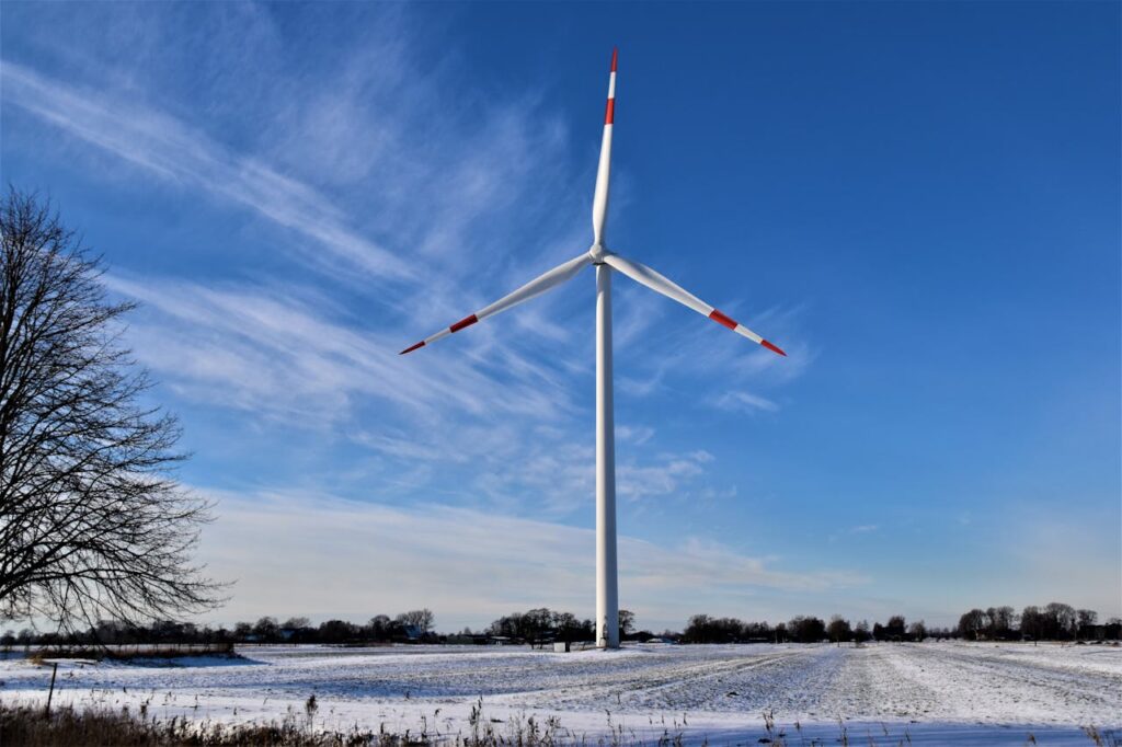Wind turbine standing in a snow-covered field under a clear blue sky in Raa-Besenbek, Germany.
